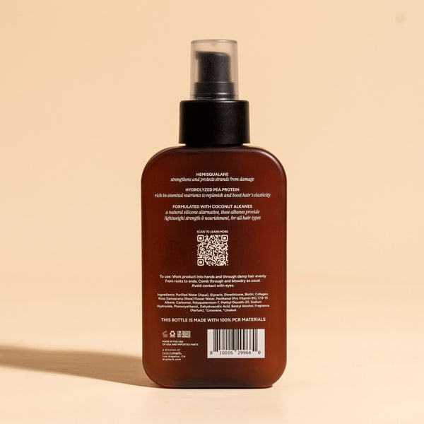 photograph of the back of a brown bottle with black pump and light green text printed on it. the product is on a tan background with a large shadow behind it