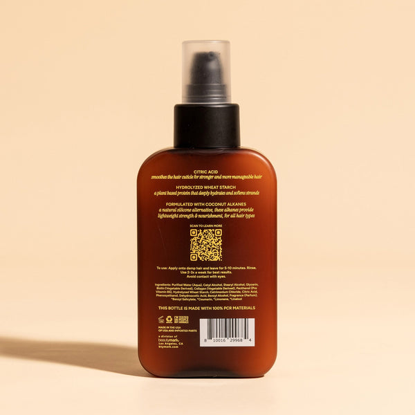photograph of the back of a brown bottle with black pump and light green text printed on it. the product is on a tan background with a large shadow behind it