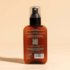 photograph of the back of a brown bottle with black pump and light green text printed on it. the product is on a tan background with a large shadow behind it