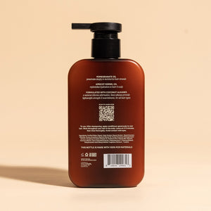 photograph of the back of a brown bottle with black pump and light green text printed on it. the product is on a tan background with a large shadow behind it