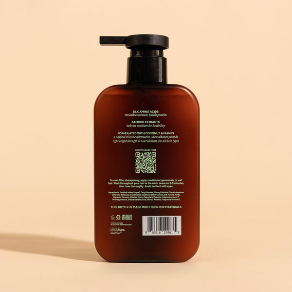 photograph of the back of a brown bottle with black pump and light green text printed on it. the product is on a tan background with a large shadow behind it