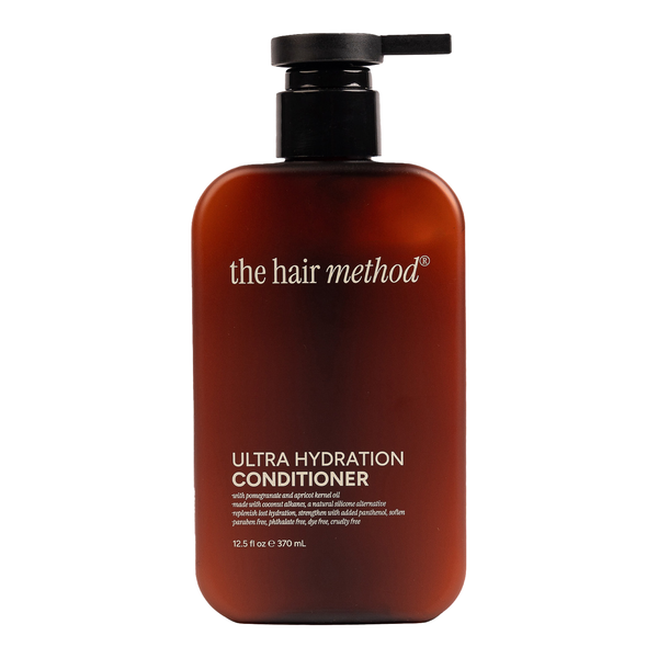 Brown conditioner bottle with black pump labeled 'the hair method' on a white background
