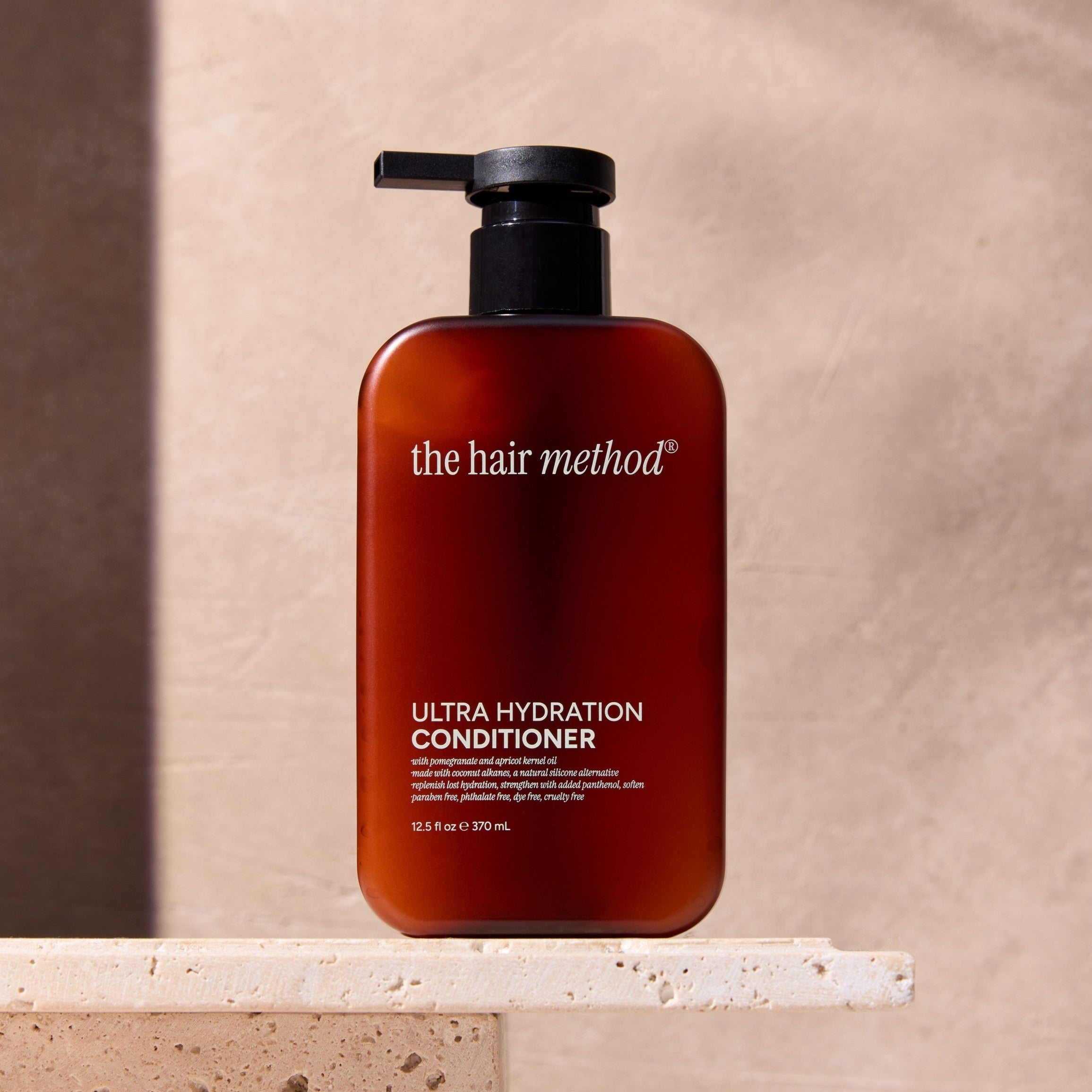 The Hair Method ultra hydration conditioner bottle on a stone surface with a neutral background