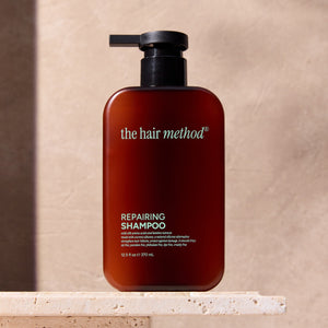 The Hair Method repairing shampoo bottle on a stone surface with a neutral background