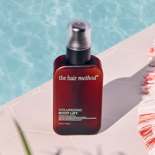 Amber bottle of 'the hair method' product on a ledge with water in the background